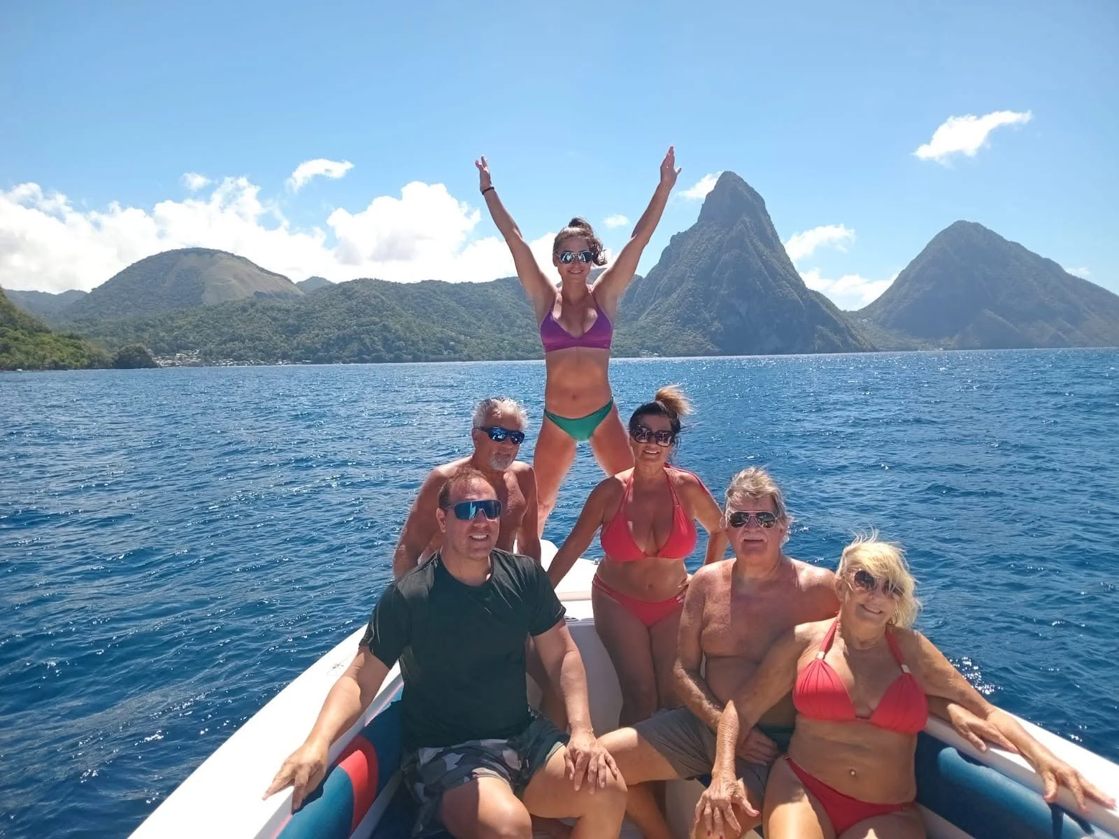 Guests celebrating on the bow of a Real Deal boat with the Pitons behind them, Saint Lucia